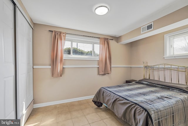 bedroom featuring light tile patterned floors, a closet, visible vents, and baseboards