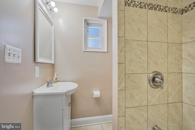 bathroom featuring tile patterned floors, baseboards, a tile shower, and vanity