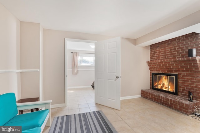 living area featuring a brick fireplace, light tile patterned flooring, and baseboards