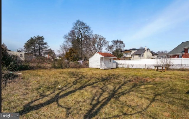 view of yard featuring a storage shed, fence, and an outbuilding