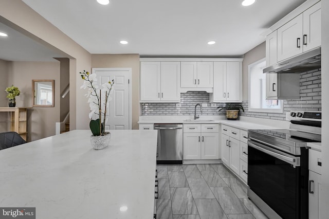 kitchen featuring under cabinet range hood, a sink, white cabinets, appliances with stainless steel finishes, and backsplash