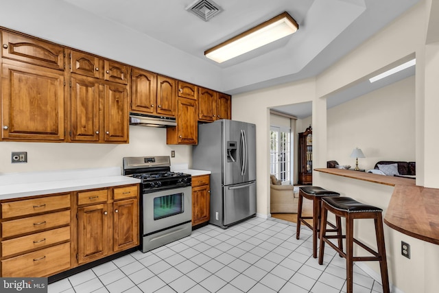 kitchen featuring visible vents, brown cabinets, stainless steel appliances, under cabinet range hood, and light tile patterned flooring