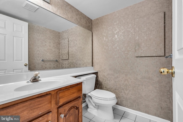 half bath with visible vents, toilet, vanity, baseboards, and tile patterned floors