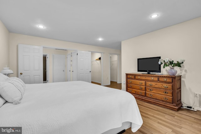 bedroom featuring light wood-type flooring, a spacious closet, baseboards, and recessed lighting