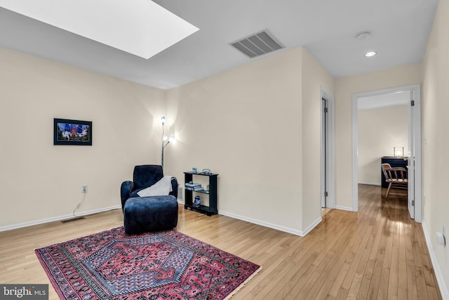 sitting room with a skylight, wood-type flooring, and visible vents