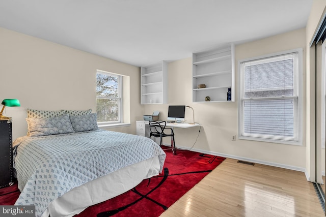 bedroom with wood finished floors, visible vents, and baseboards