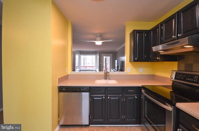 kitchen with under cabinet range hood, appliances with stainless steel finishes, light countertops, and a sink