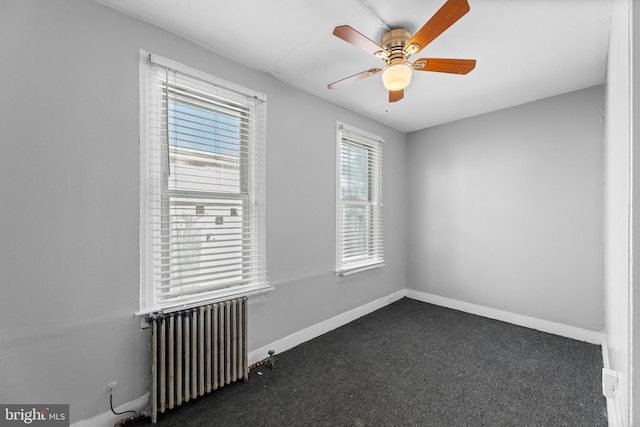 empty room with carpet floors, radiator, ceiling fan, and baseboards