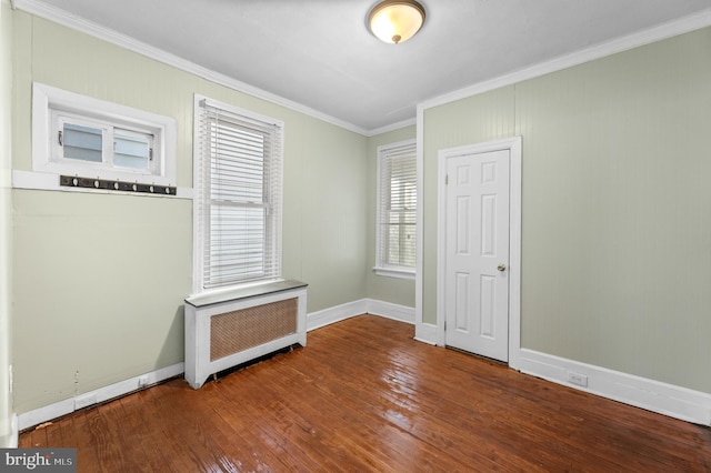 empty room with baseboards, crown molding, hardwood / wood-style floors, and radiator heating unit