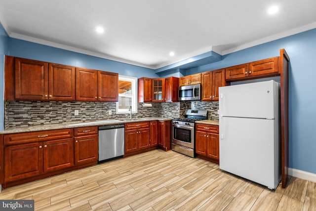 kitchen featuring a sink, light wood-style floors, ornamental molding, appliances with stainless steel finishes, and decorative backsplash