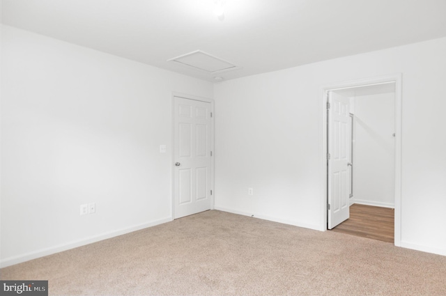 spare room with carpet flooring, attic access, and baseboards