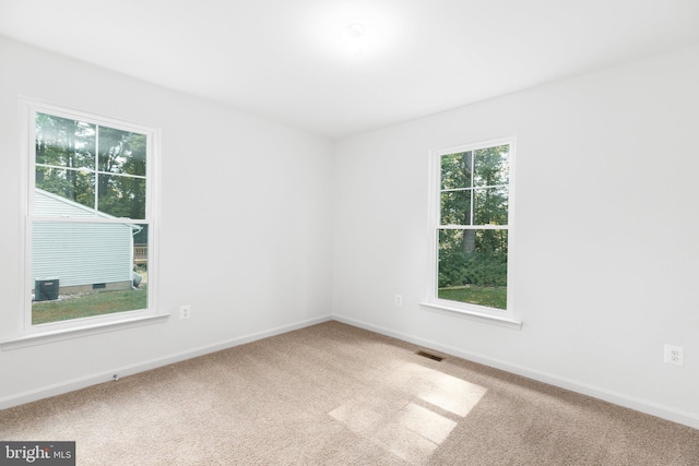 carpeted spare room featuring visible vents and baseboards