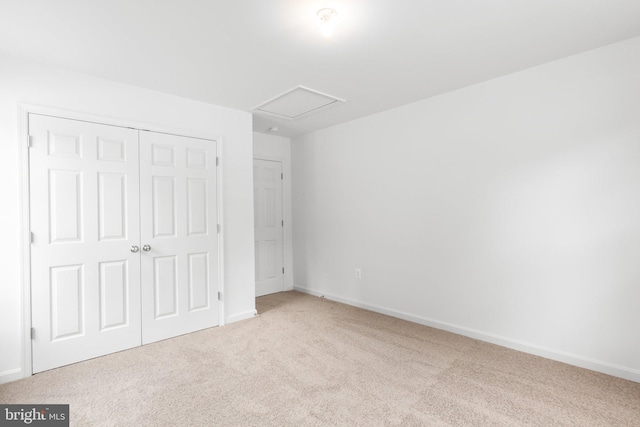 unfurnished bedroom with carpet floors, attic access, a closet, and baseboards