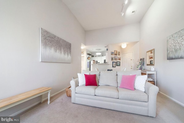 living room featuring visible vents, baseboards, a towering ceiling, rail lighting, and carpet flooring