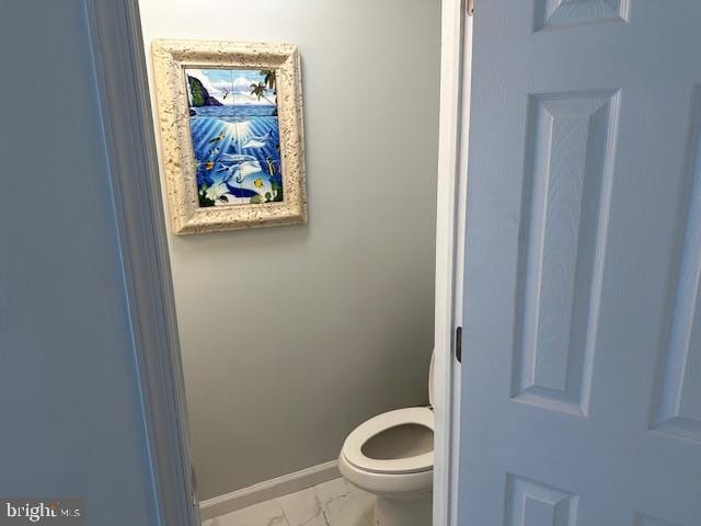 bathroom with marble finish floor, toilet, and baseboards