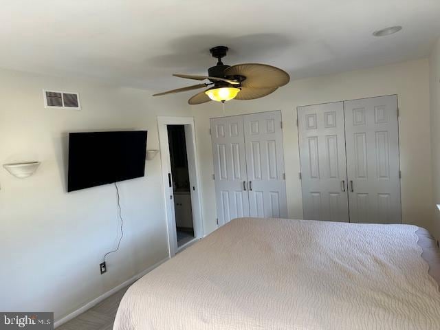 bedroom with baseboards, a ceiling fan, visible vents, and multiple closets