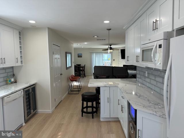 kitchen featuring wine cooler, white appliances, white cabinets, light wood-type flooring, and open shelves