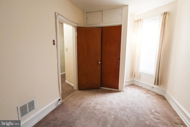 unfurnished bedroom featuring light carpet, a closet, visible vents, and baseboards