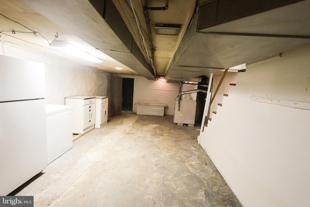 unfinished basement featuring stairs, freestanding refrigerator, heating unit, and fridge