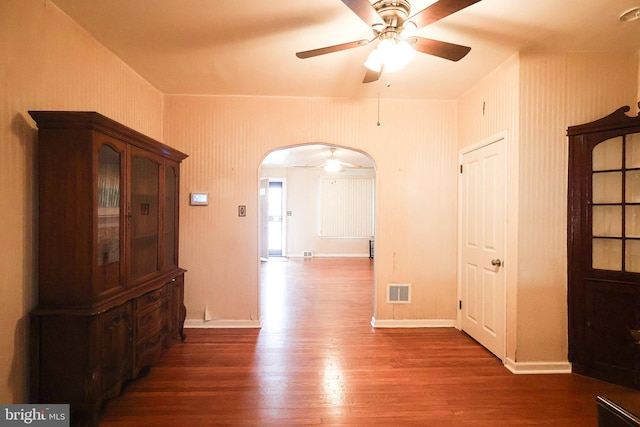 spare room featuring arched walkways, visible vents, ceiling fan, wood finished floors, and baseboards