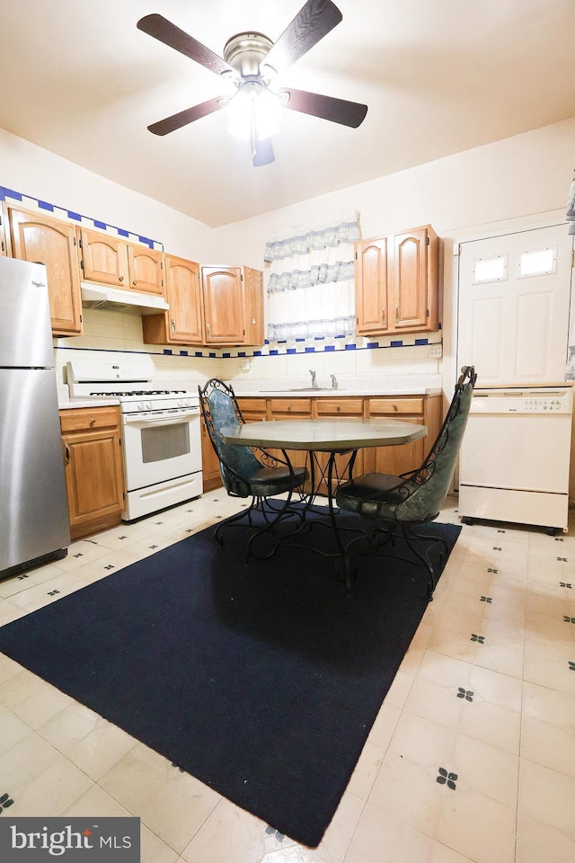 kitchen with freestanding refrigerator, light countertops, white gas stove, and a sink