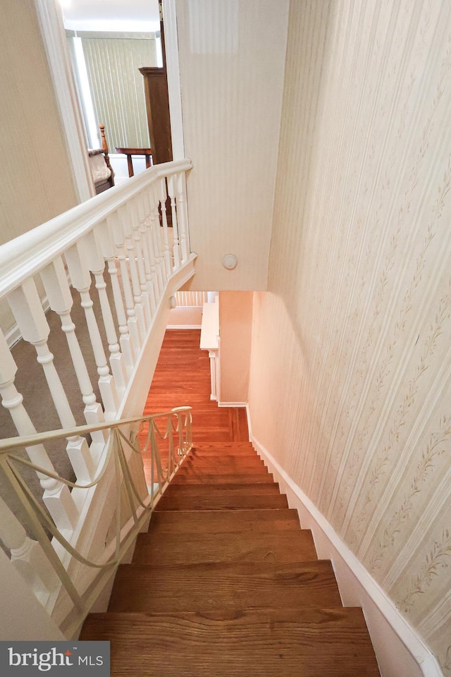 stairway with baseboards and wallpapered walls