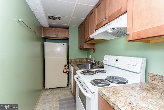 kitchen featuring a sink, white appliances, baseboards, under cabinet range hood, and visible vents