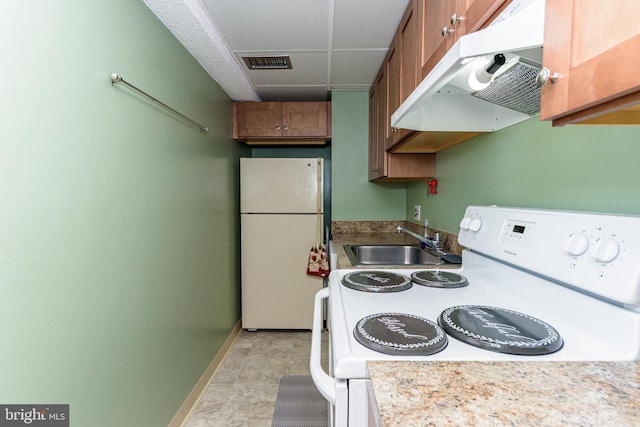 kitchen featuring a sink, visible vents, baseboards, white appliances, and under cabinet range hood
