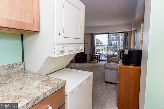 clothes washing area with stacked washer and dryer, laundry area, and carpet