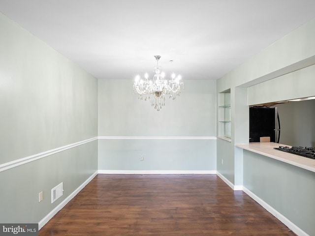 unfurnished dining area with built in features, baseboards, a chandelier, and wood finished floors