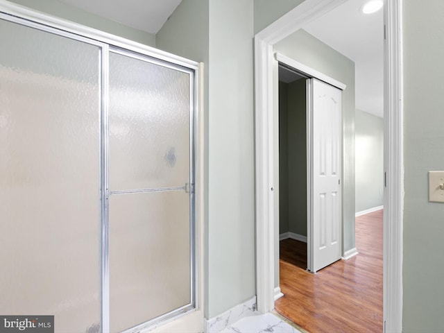 full bathroom featuring a shower stall, baseboards, and wood finished floors