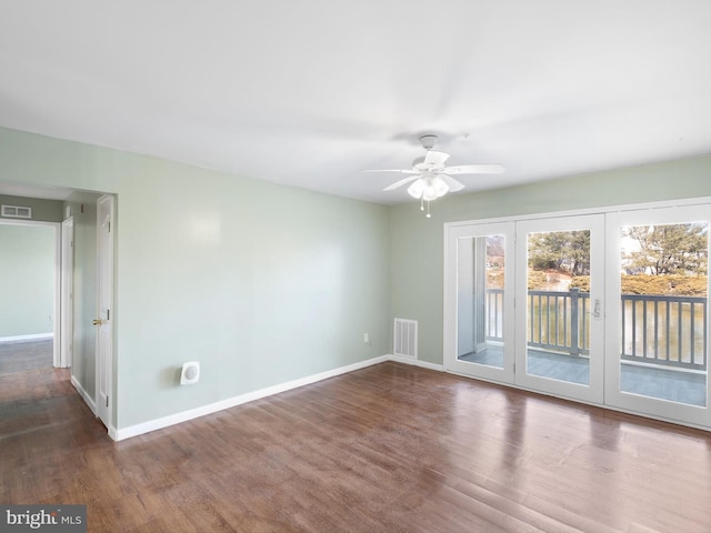 empty room featuring a ceiling fan, visible vents, baseboards, and wood finished floors