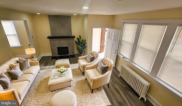 living room featuring a tile fireplace, baseboards, radiator heating unit, and wood finished floors