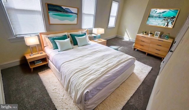 bedroom with dark colored carpet and baseboards