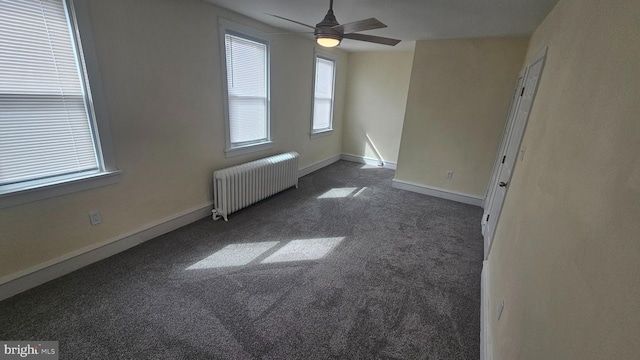 spare room with ceiling fan, dark colored carpet, radiator heating unit, and baseboards