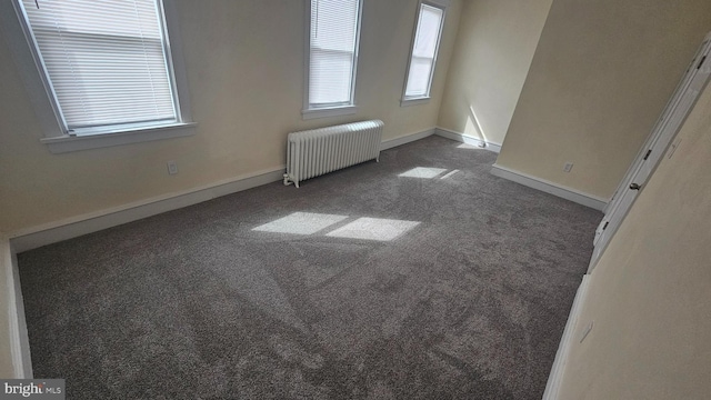 spare room with radiator, carpet, and baseboards