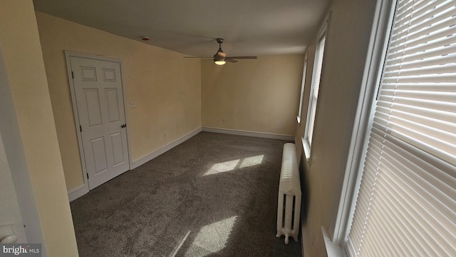 spare room featuring radiator heating unit, carpet flooring, a ceiling fan, and baseboards