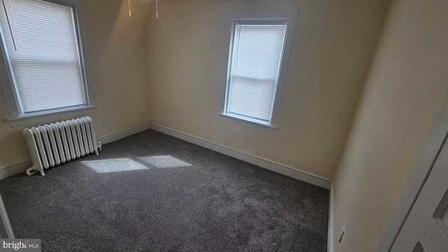 carpeted empty room with radiator and baseboards