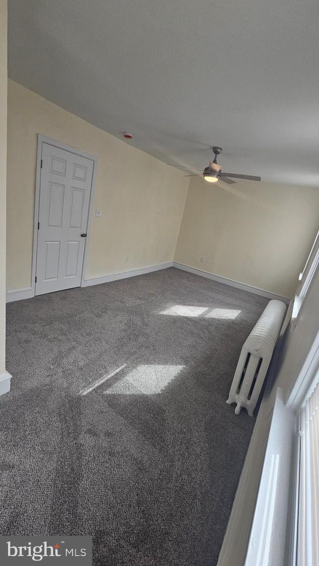 carpeted spare room with a ceiling fan and baseboards