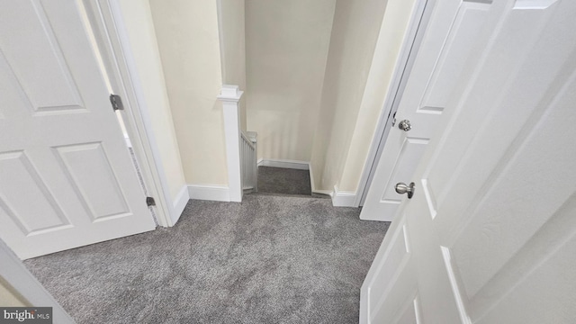 hallway featuring carpet floors, baseboards, and an upstairs landing