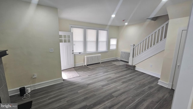 unfurnished living room featuring baseboards, wood finished floors, stairs, and radiator