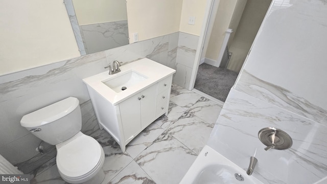 full bathroom featuring marble finish floor, a bathtub, vanity, and toilet