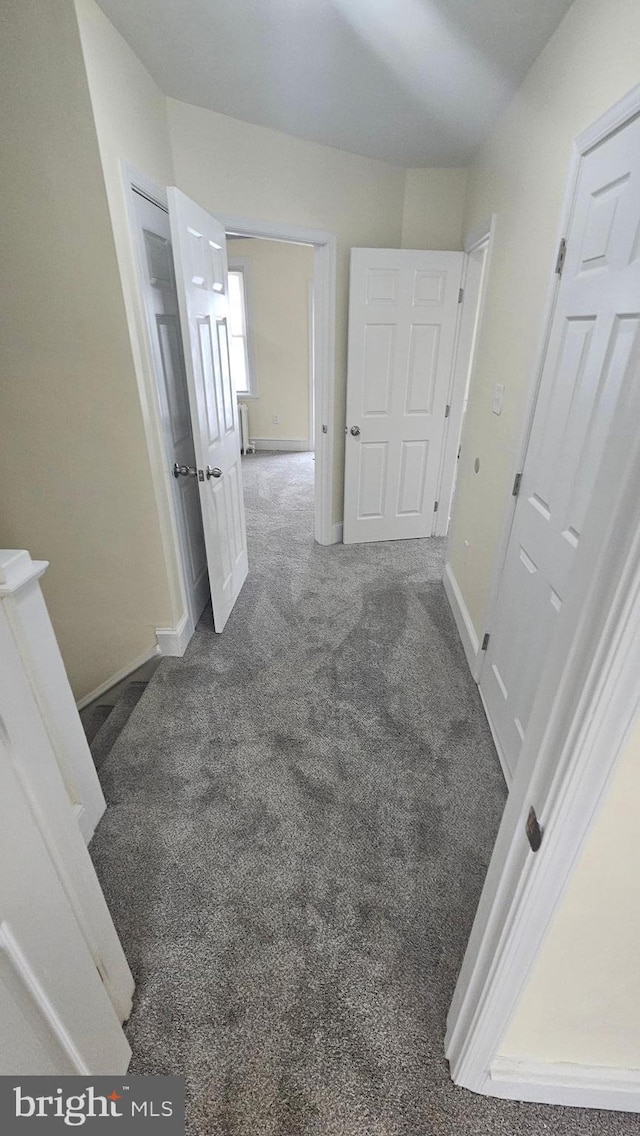 hall with baseboards and carpet flooring