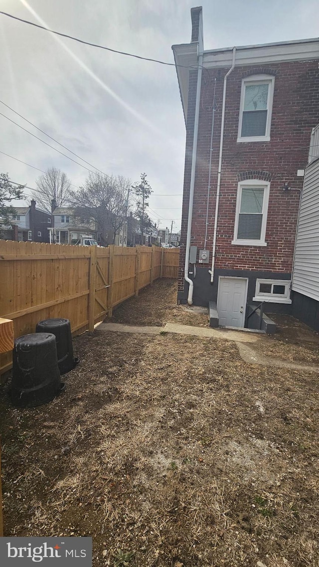 exterior space with brick siding and a fenced backyard