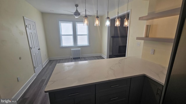 kitchen featuring light stone counters, radiator, dark wood finished floors, and a peninsula