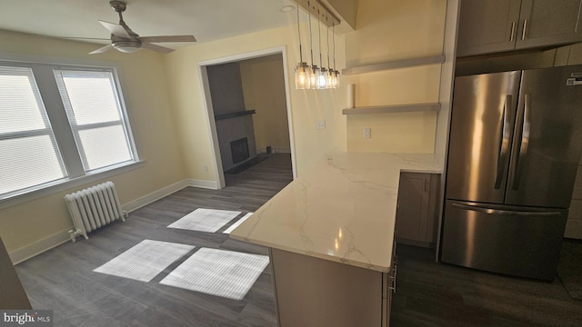 kitchen featuring a fireplace, baseboards, freestanding refrigerator, radiator heating unit, and dark wood finished floors