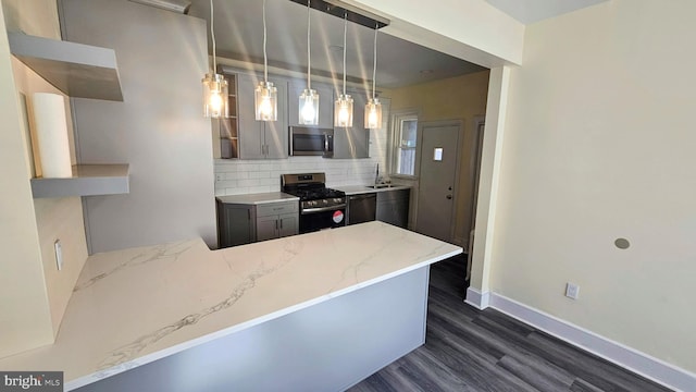 kitchen featuring dark wood-style floors, light stone counters, a peninsula, stainless steel appliances, and backsplash