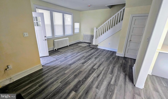 unfurnished living room with radiator, stairway, baseboards, and wood finished floors