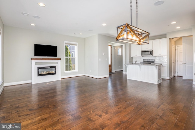 kitchen featuring backsplash, open floor plan, white cabinets, stainless steel appliances, and dark wood-style flooring