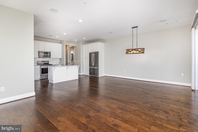 unfurnished living room featuring dark wood-type flooring, recessed lighting, baseboards, and a sink